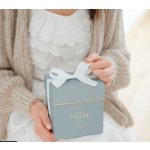 Person holding a blue gift box with a white ribbon