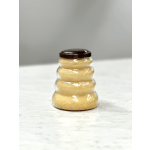 Beehive-shaped plastic jar filled with light golden contents and a dark brown lid on a light surface.