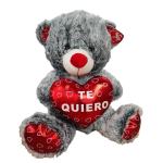 Gray teddy bear holding a red heart that says "TE QUIERO"