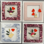 Four framed paper crafts with hearts and small floral accents.