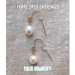 Pair of pearl drop earrings on a textured fabric background