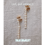 Pair of pearl drop earrings on a textured fabric background