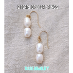 Pair of pearl drop earrings with gold hooks on a fabric background