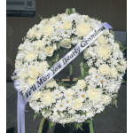 White funeral wreath with a memorial ribbon on a stand