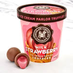 Pink tub of milk strawberry chocolate truffles with two candies beside it
