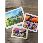 Three colorful landscape art prints on a wooden surface