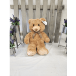 Large teddy bear with a checkered bow, flanked by small purple flower arrangements