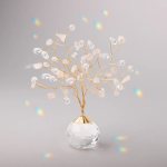 Gold wire gemstone tree with clear and blush crystals in a faceted glass base on a gray background