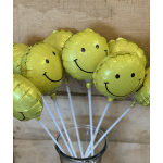 Yellow smiley-face balloons in a glass vase
