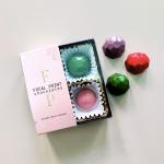 Box of colorful chocolates with three loose pieces beside it