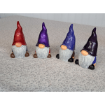 Four painted gnome figurines with tall hats on a patterned surface