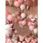 Pink, white, and metallic heart balloons fill a room