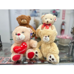 Four teddy bears displayed on a shelf, one holding a red heart