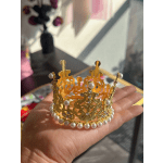 Gold jeweled crown with pearl accents resting in a hand