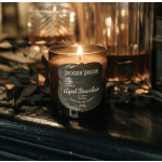 Lit amber candle in a glass jar with a dark label