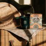 A straw hat beside a lit candle and a Nashville gift box on a suitcase