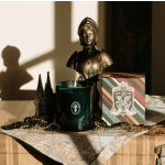 A candle, decorative bust, and New Orleans box arranged on a table