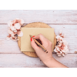 Hand writing on a card beside pale pink flowers