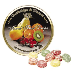 Round tin of mixed fruit drops with assorted candies beside it