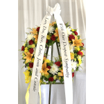 Large standing floral wreath with white condolence ribbons