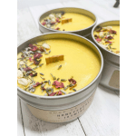 Three yellow candles in metal tins topped with dried flower petals