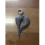 Silver wing-shaped charm on a wooden surface