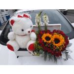 White teddy bear beside a box of red roses and sunflowers
