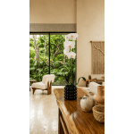 White orchid stems in a black vase on a wooden table.