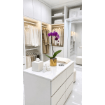 Purple orchid in a gold pot on a white island in a walk-in closet.