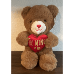 Brown teddy bear holding a red heart pillow