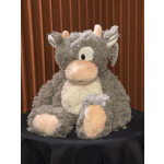 Gray plush cow toy with pink accents sitting on a black cloth