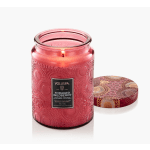Pink scented candle in a decorative glass jar with a patterned lid