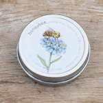 Round metal tin with a bee and blue flower illustration on the lid