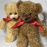 Two plush teddy bears with red ribbons sitting together
