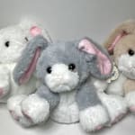 Three plush bunny toys in gray, white, and beige