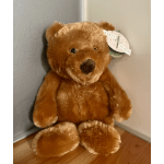 Brown teddy bear with a tag sitting on the floor