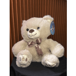 Plush teddy bear with a satin bow sitting against a brown curtain