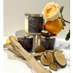 Three scented candles with an orange rose and citrus slices