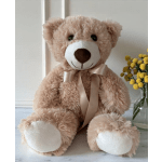 Teddy bear with a satin ribbon beside yellow pom-pom flowers in a vase