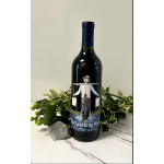 Wine bottle with greenery and a crystal on a tabletop