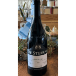 Bottle of red wine on a wooden table with decorative plants in the background
