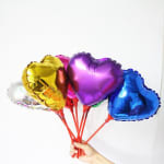 Hand holding a bunch of heart-shaped foil balloons in bright colors