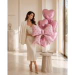 Woman holding pink heart-shaped balloons and a large pink bow balloon