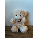 Cream teddy bear with a polka-dot ribbon sitting on a wooden surface