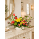 Colorful mixed flower arrangement in a white vase on a table