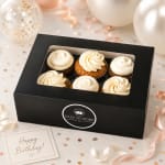 Box of frosted cupcakes with a birthday card and ribbon decorations