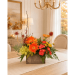 Orange and red floral arrangement in a wooden box on a dining table