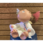 Small angel figurine with colorful wings sitting on a blue base