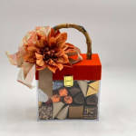 Gift box of assorted chocolates topped with an orange flower and ribbon
