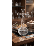 Clear glass cross on a wooden table beside a gift box